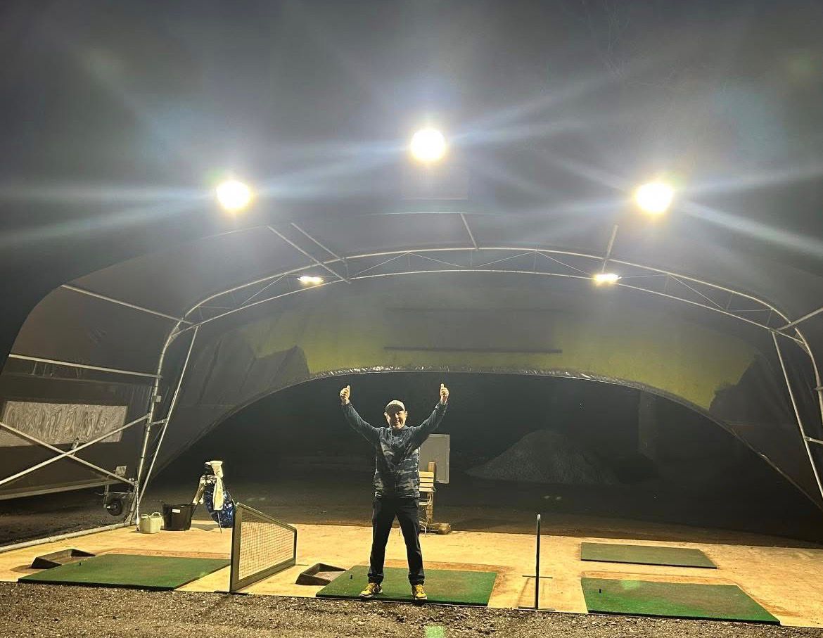 Lit driving range with the club professional standing under the new LED floodlights