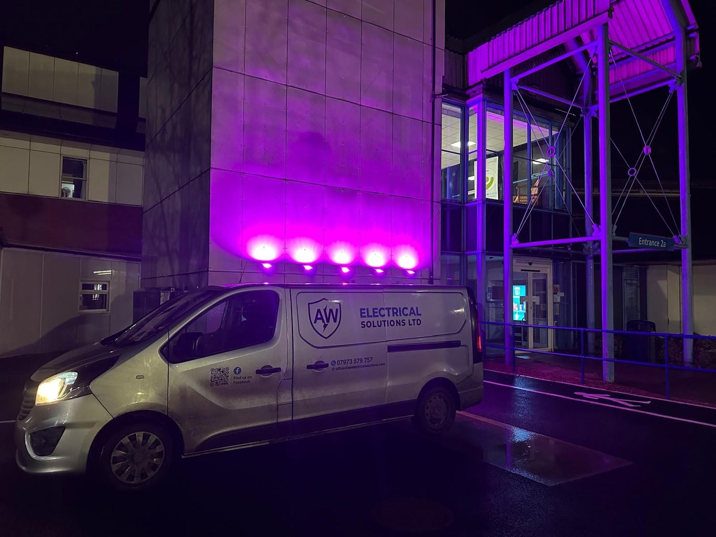 AW Electrical van outside an illuminated NHS entrance at night